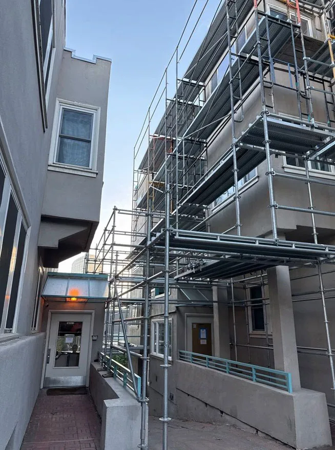 Huntington Beach Scaffolding installation in narrow commercial walkway with multi-level frame system for exterior building access